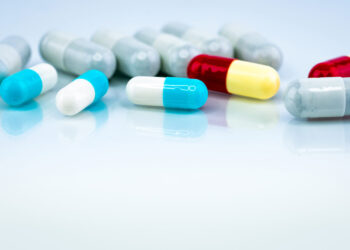 Colorful capsule pills on white background. Pharmaceutical industry. Herbal medicine interaction with other drug. Pharmaceutics. Pharmacy drugstore concept. Blue, white, red, and yellow capsule pills.