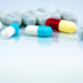 Colorful capsule pills on white background. Pharmaceutical industry. Herbal medicine interaction with other drug. Pharmaceutics. Pharmacy drugstore concept. Blue, white, red, and yellow capsule pills.