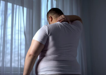 Obese man stretching neck muscles, back pain problems caused by overweight